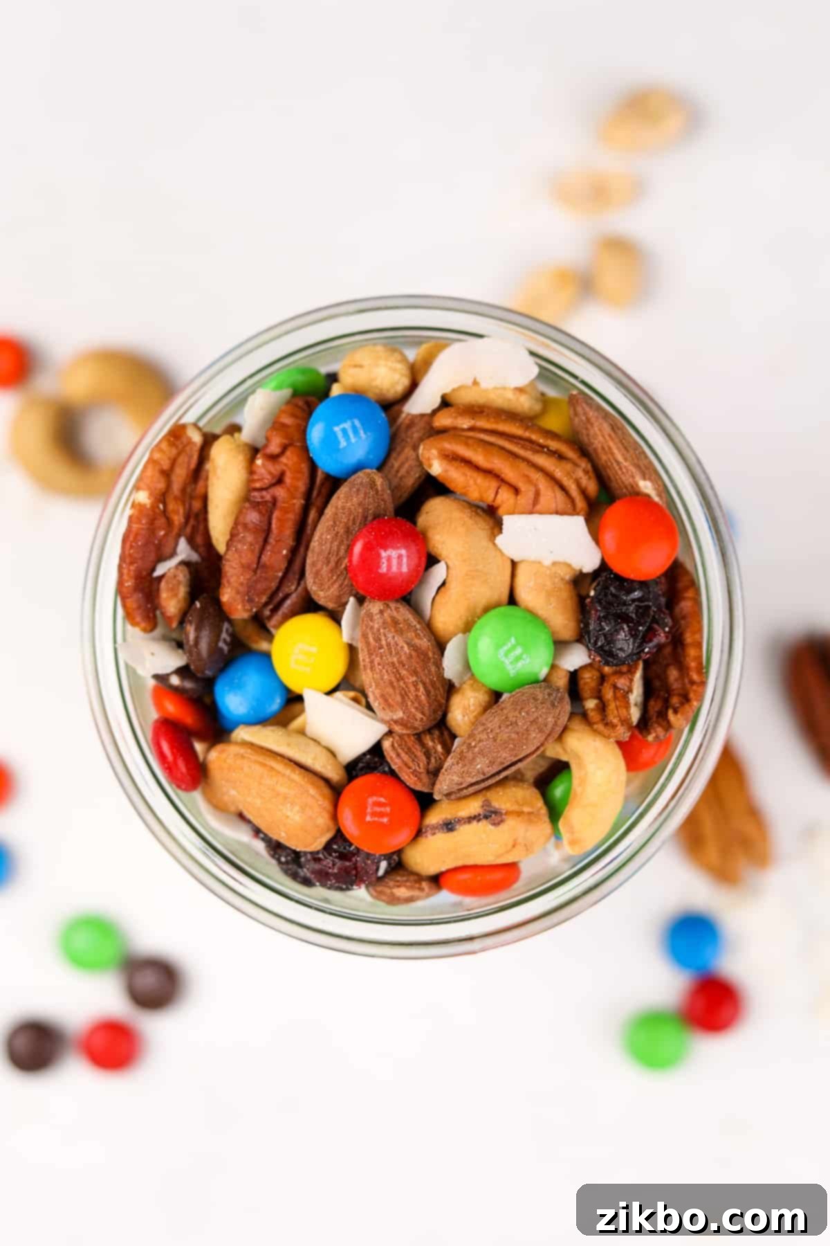 An overhead view of a mason jar filled with a colorful and delicious homemade trail mix, showcasing the layers of nuts, dried fruit, and chocolate.