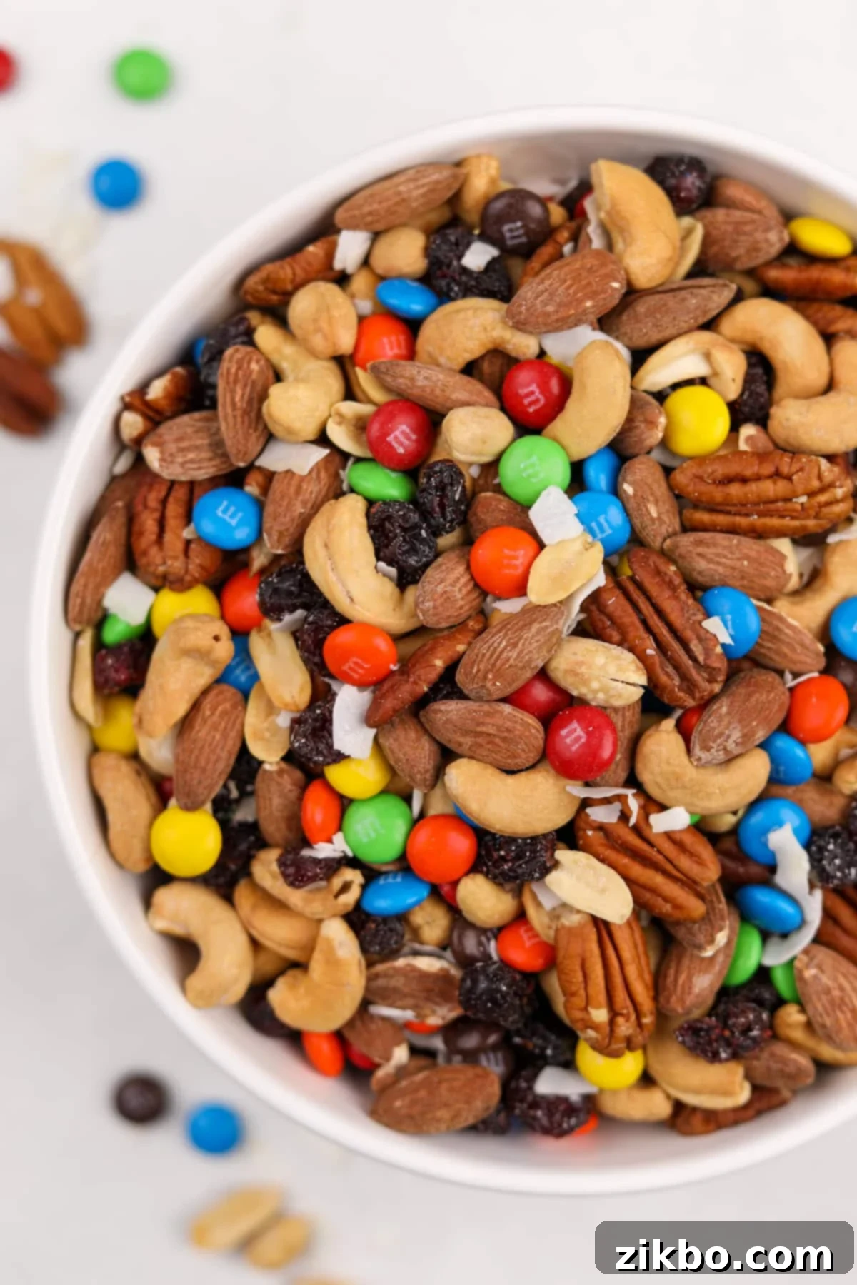 A big white bowl filled with a generous amount of homemade trail mix, beautifully dotted with vibrant M&M's.