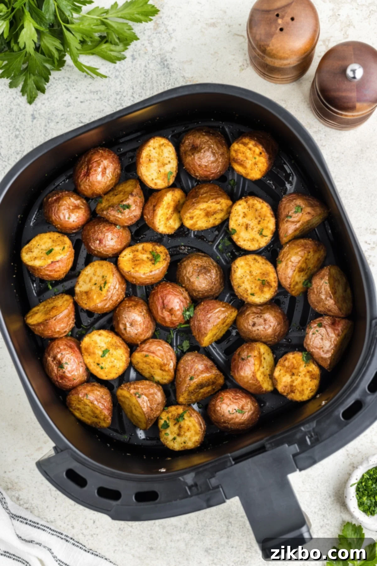 An air fryer basket filled with roasted baby red potatoes, glistening and golden brown.