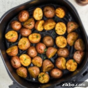 An air fryer basket filled with perfectly roasted baby potato halves, ready to serve.