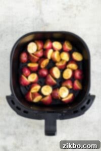 An air fryer basket filled with seasoned baby red potatoes, carefully arranged in a single layer for even cooking.