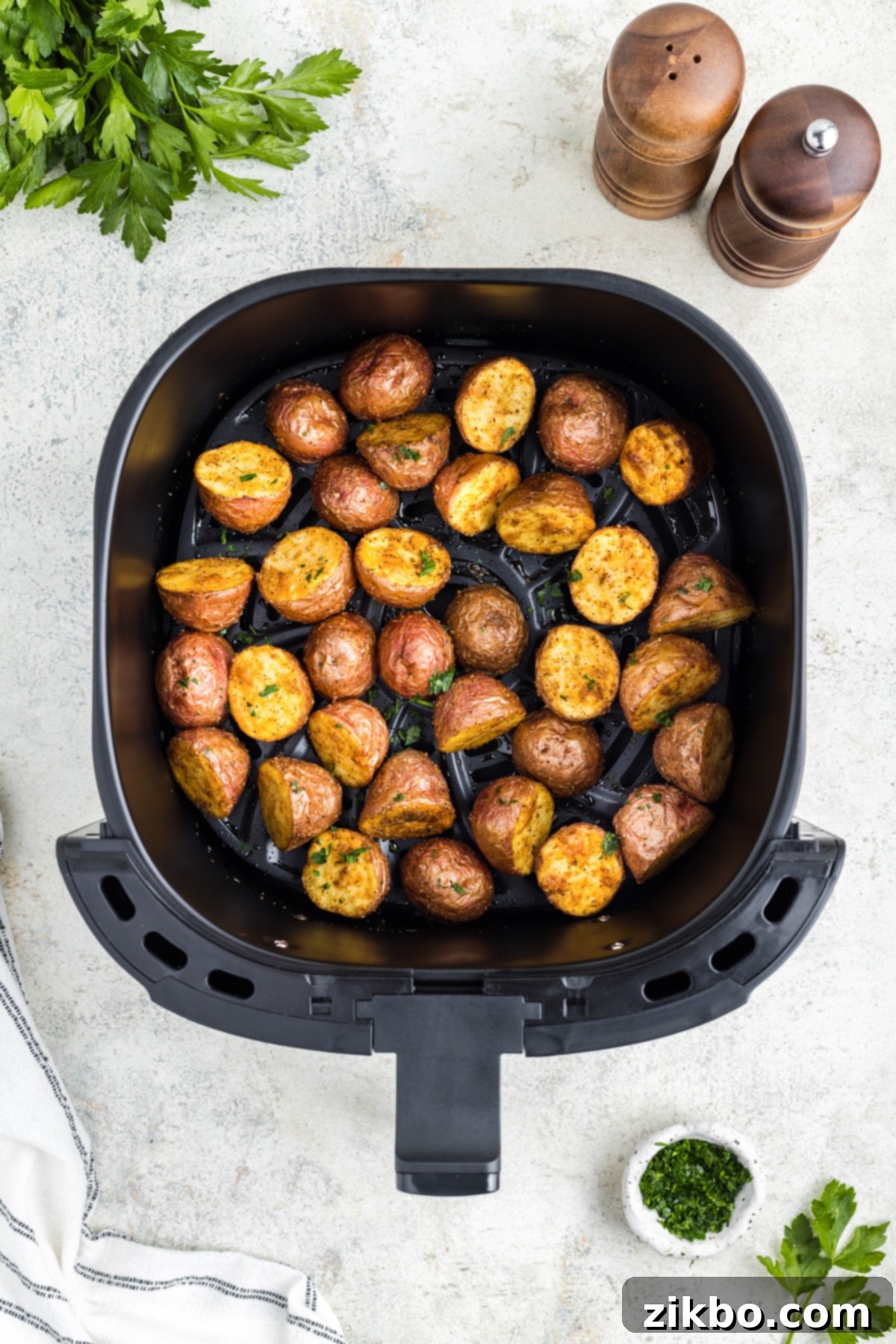 An air fryer basket with perfectly roasted and crispy baby red potatoes inside after cooking.