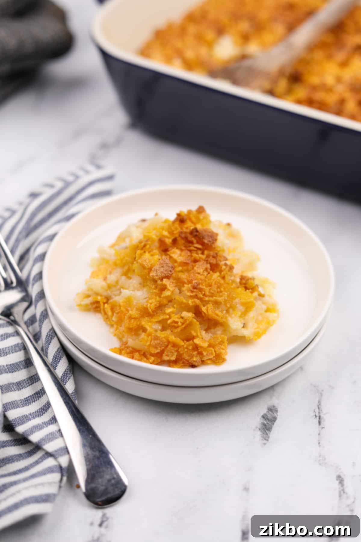 A beautifully presented plate with a generous portion of gluten-free funeral potatoes, garnished and ready to eat.