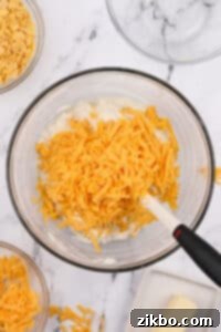 A large bowl with shredded cheddar cheese inside.
