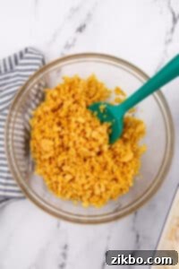 Stirring corn flakes and melted butter in a bowl.