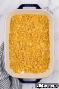 A baking dish filled with a casserole and topped with a buttery corn flake layer.