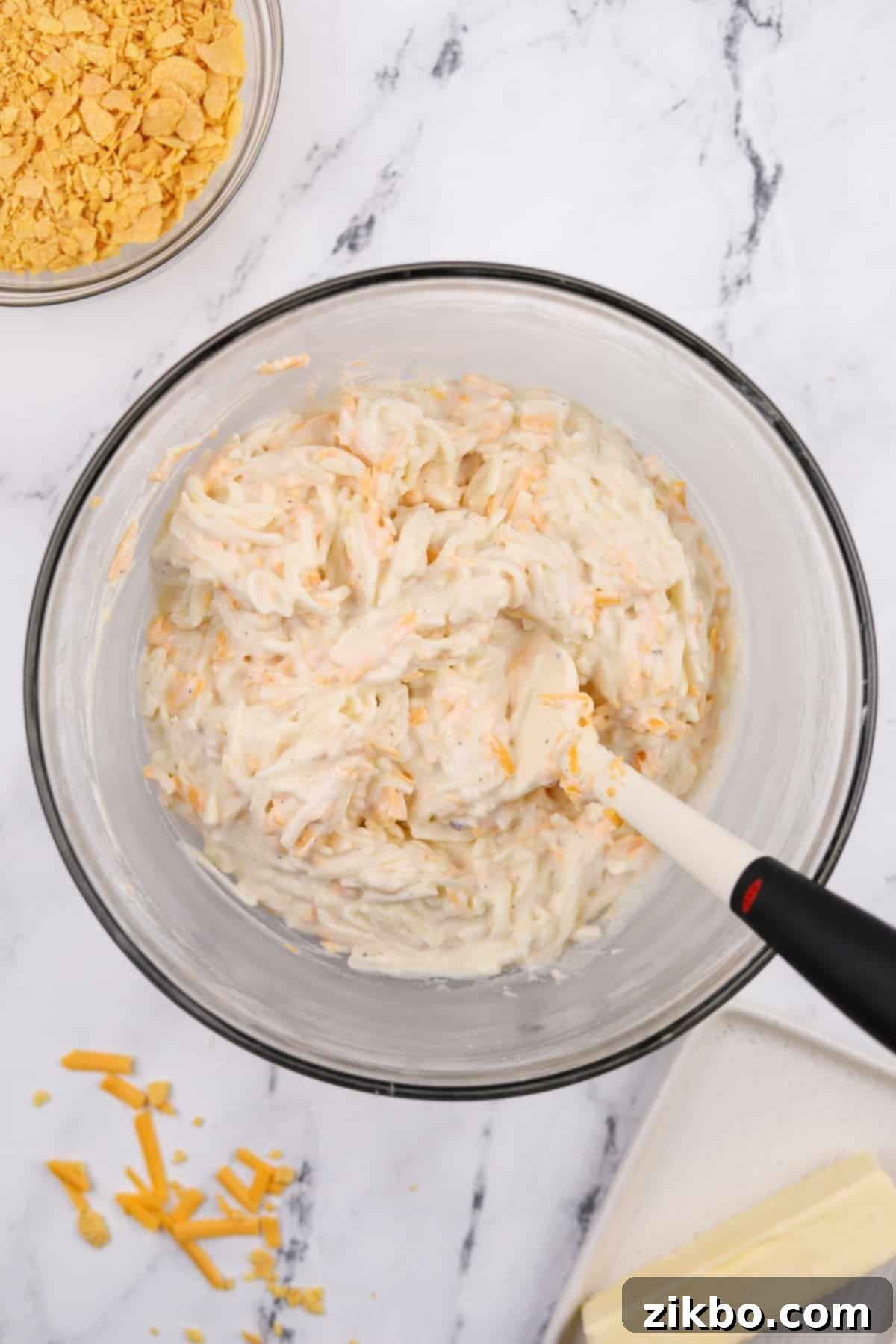 A large bowl showcasing the fully mixed hash brown casserole base, ready to be transferred to a baking dish.