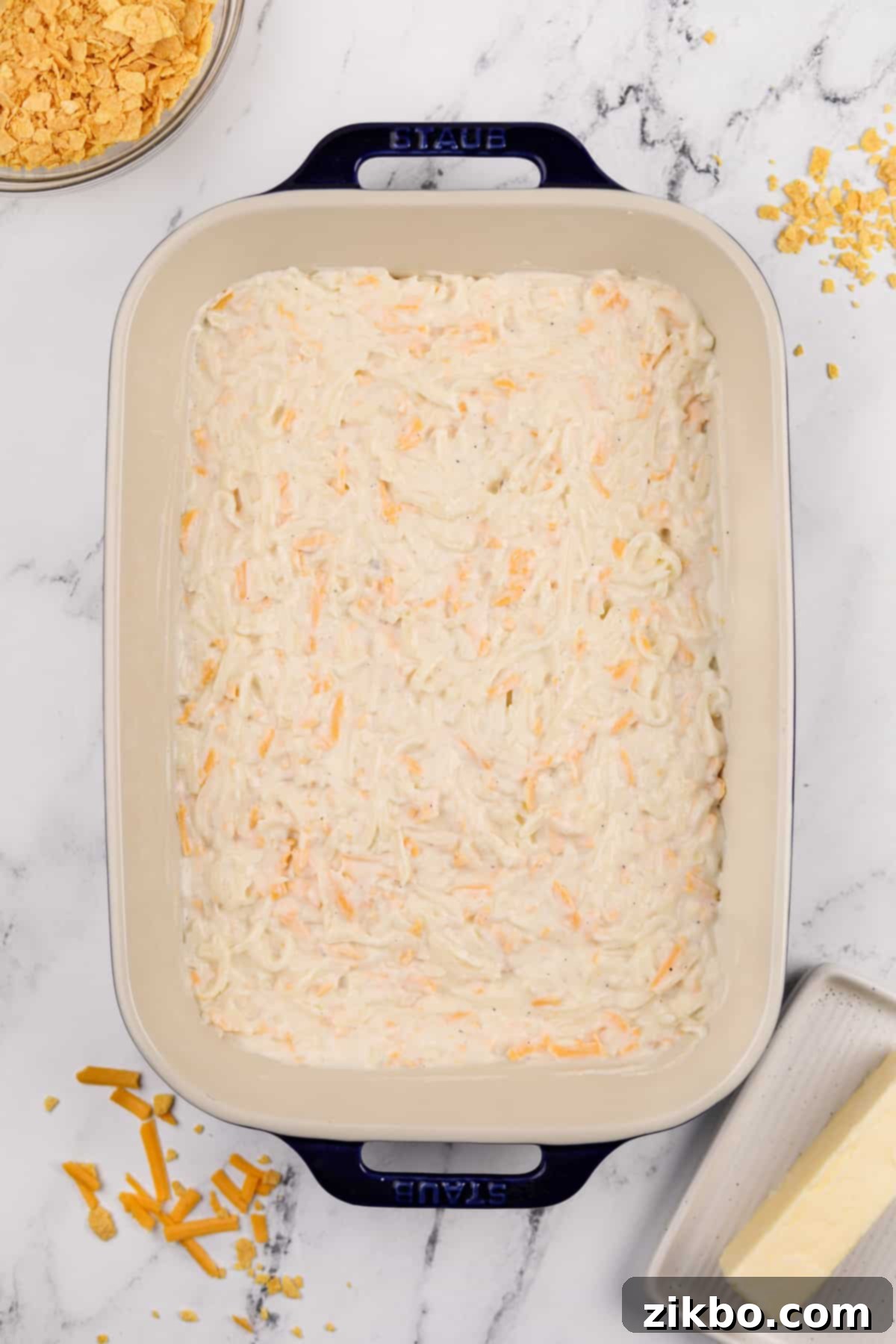 Hash brown casserole mixture evenly spread into a greased 9x13 inch baking dish, ready for the topping.