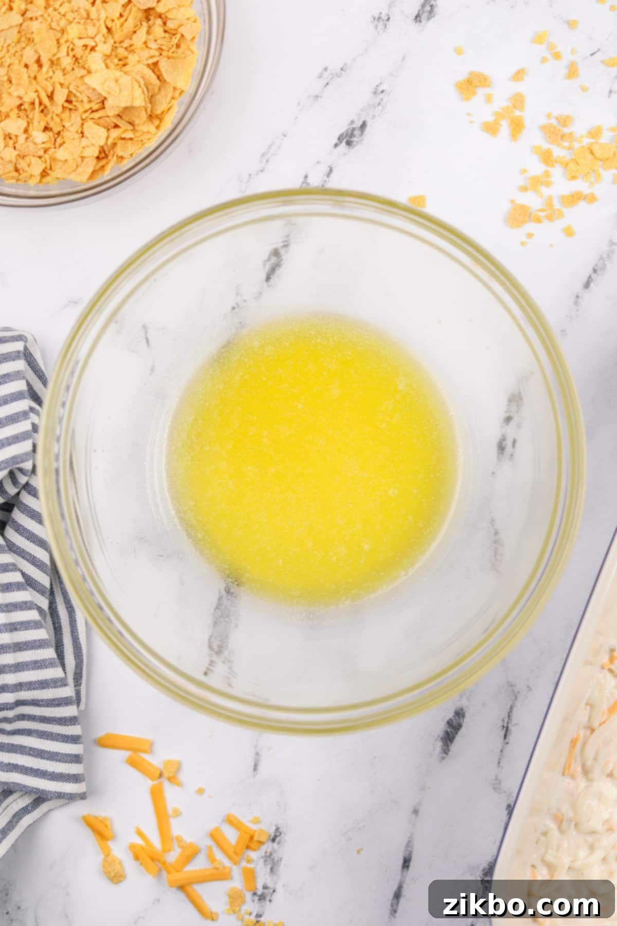 A small bowl of freshly melted butter, prepared for mixing with the corn flake topping.