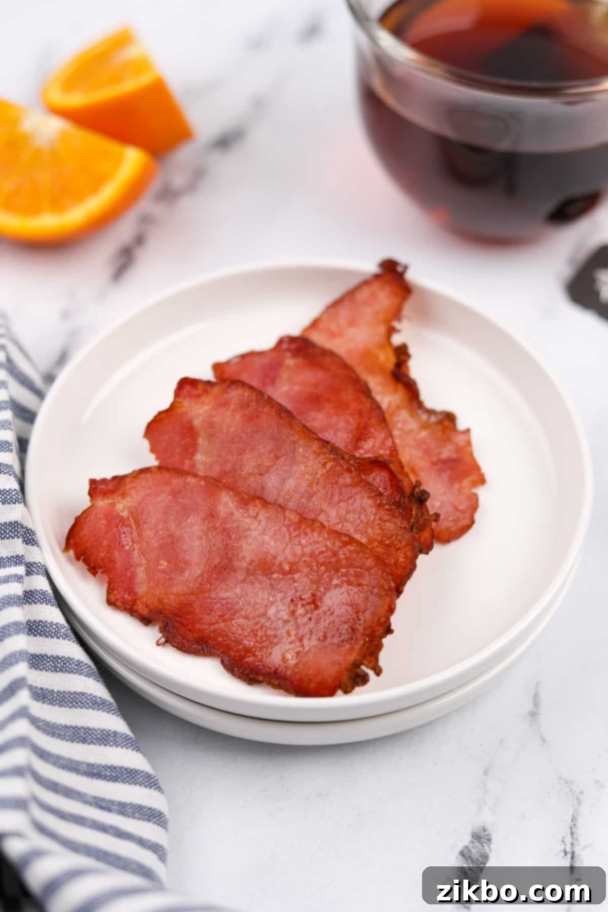 A plate with four slices of perfectly cooked, crispy back bacon.
