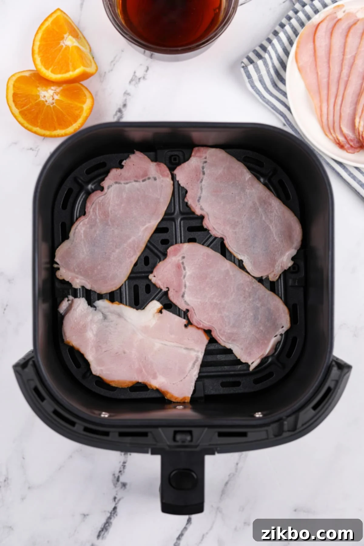 An air fryer basket with uncooked Canadian bacon slices in a single layer.