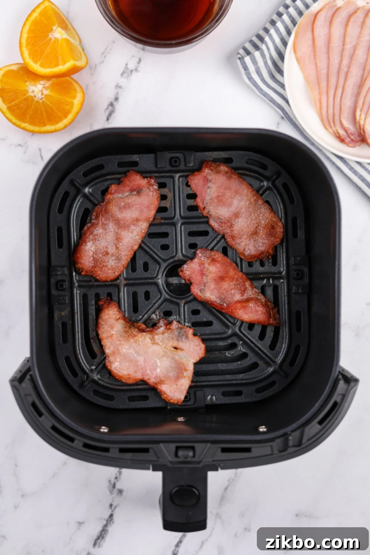 An air fryer basket with four slices of cooked, crispy back bacon.
