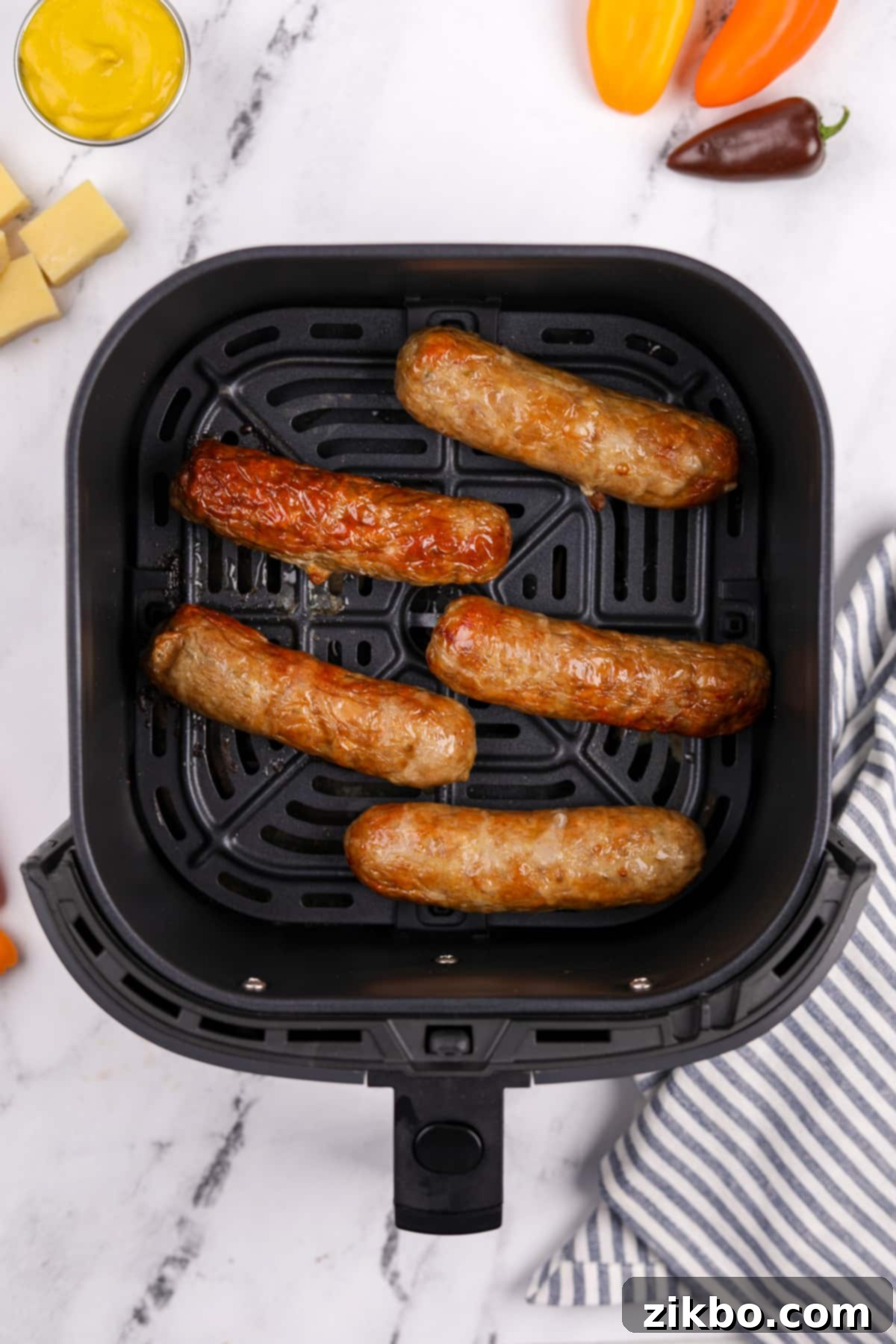 An air fryer basket showcasing perfectly cooked chicken sausages, golden-brown and crispy, after the cooking process.