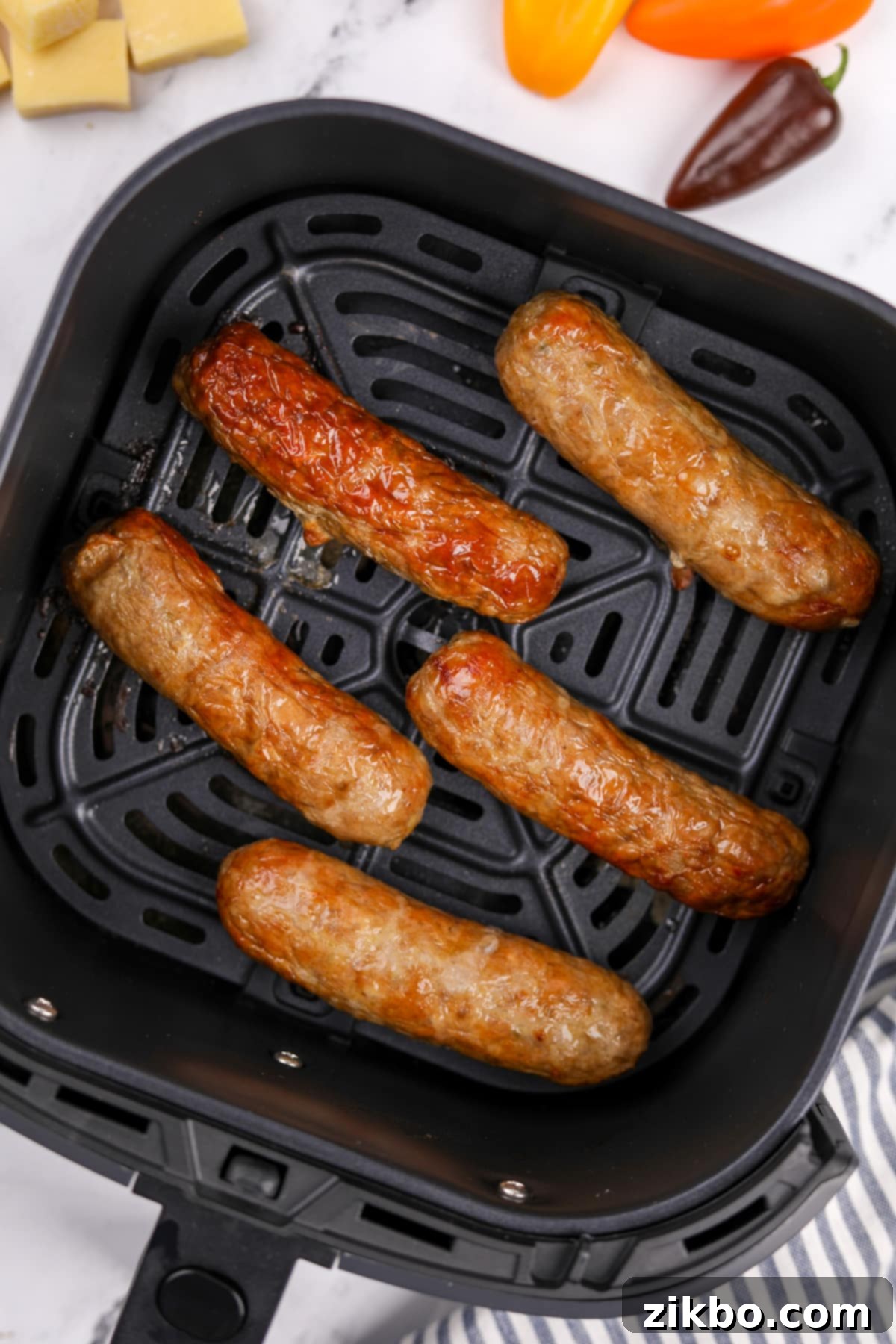 A close-up view of cooked air fryer chicken sausages nestled in the air fryer basket, showcasing their perfectly browned and crispy exterior.