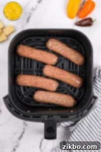 An air fryer basket with chicken sausages in a single layer.